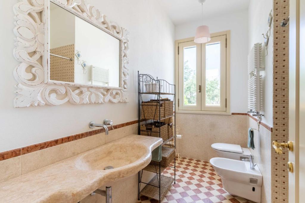La salle de bains est pourvue d'un grand miroir et d'un lavabo. dans l'établissement Villa Poggio Verde with pool - Exclusive Retreat, à Noicàttaro