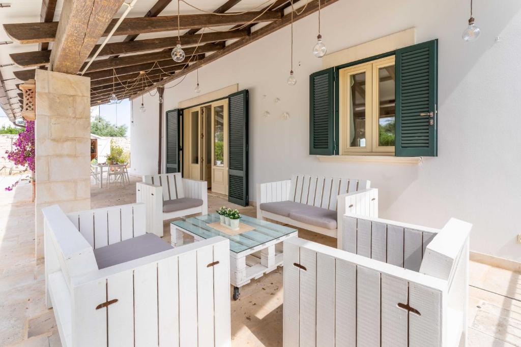 d'une terrasse avec des chaises blanches et une table. dans l'établissement Villa Poggio Verde with pool - Exclusive Retreat, à Noicàttaro