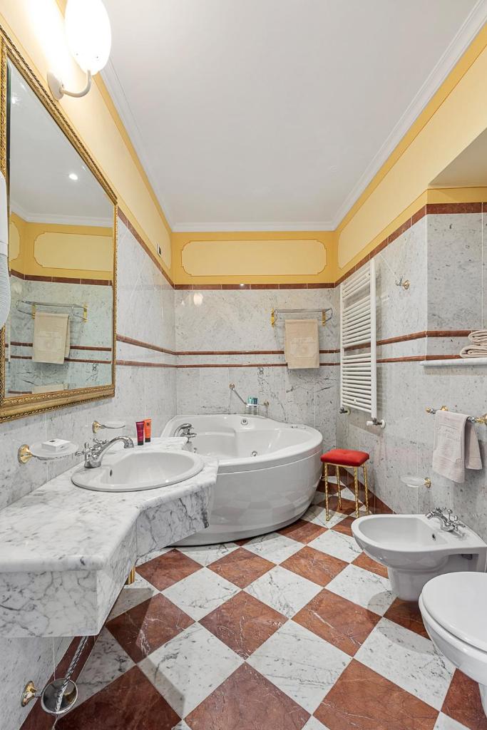 une salle de bain avec une grande baignoire et deux lavabos dans l'établissement Hotel Cannobio, à Cannobio 34 autres photos