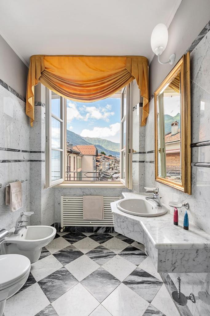 une salle de bain avec deux lavabos et une grande fenêtre dans l'établissement Hotel Cannobio, à Cannobio