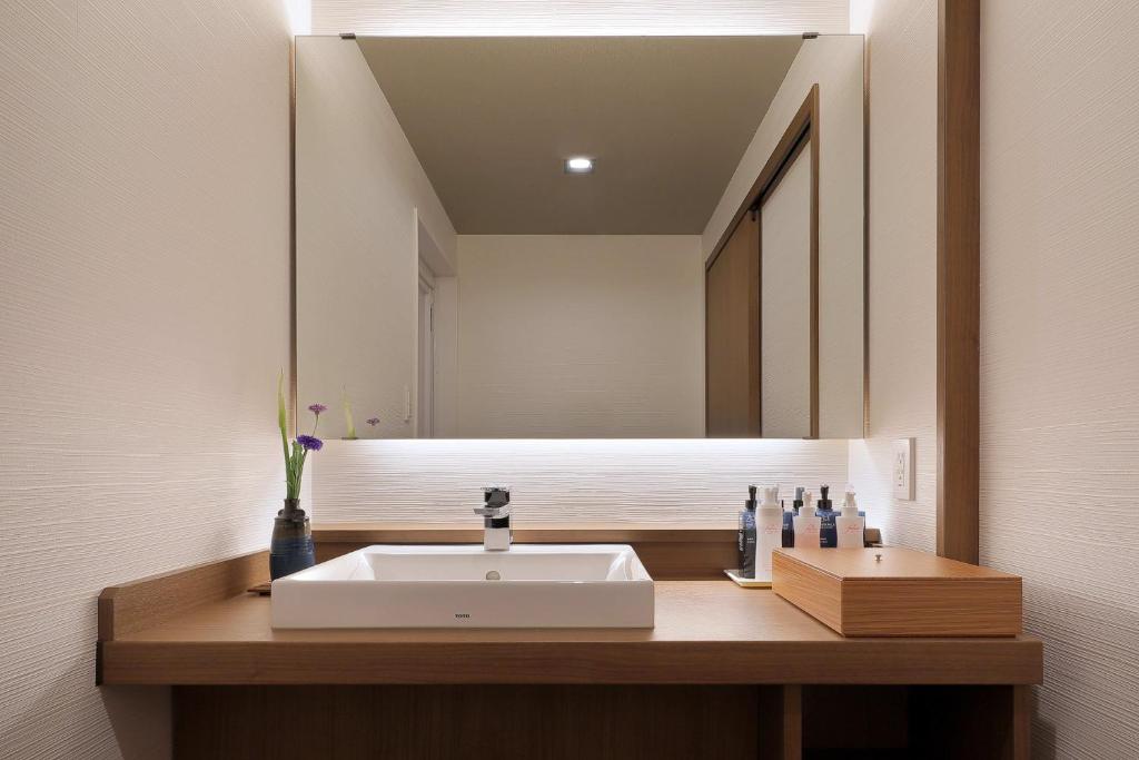 une salle de bain avec un lavabo et un miroir dans l'établissement Uminoniwa, à Kamogawa 37 autres photos
