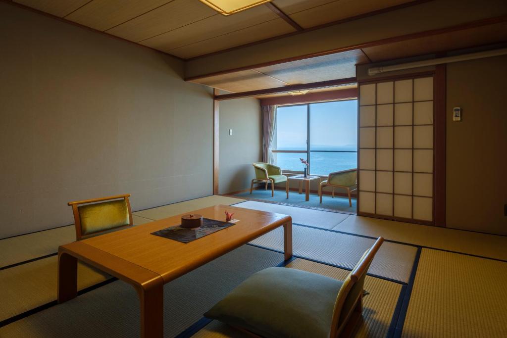 Cette chambre dispose d'une table et de chaises et offre une vue sur l'océan. dans l'établissement Fufurotenburonoyado Ginsyou, à Ibusuki