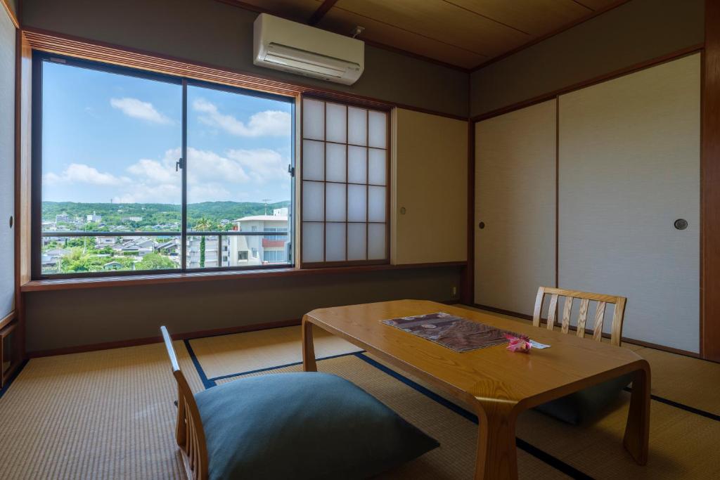 une pièce avec une table et une grande fenêtre dans l'établissement Fufurotenburonoyado Ginsyou, à Ibusuki 34 autres photos