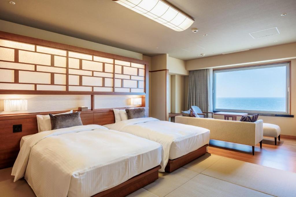 une chambre avec deux lits et une grande fenêtre dans l'établissement Hotel Oosado, à Sado