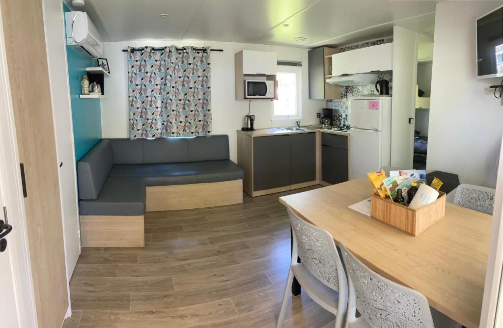 Il comprend un salon et une cuisine avec une table et un canapé. dans l'établissement Mobil home confort 6 pers, à Seignosse
