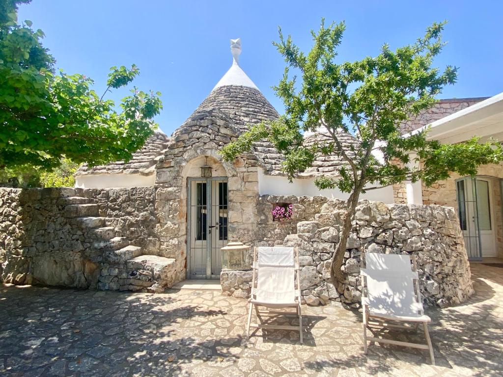 deux chaises assises devant un bâtiment en pierre dans l'établissement Maison Trullo, à Ceglie Messapica