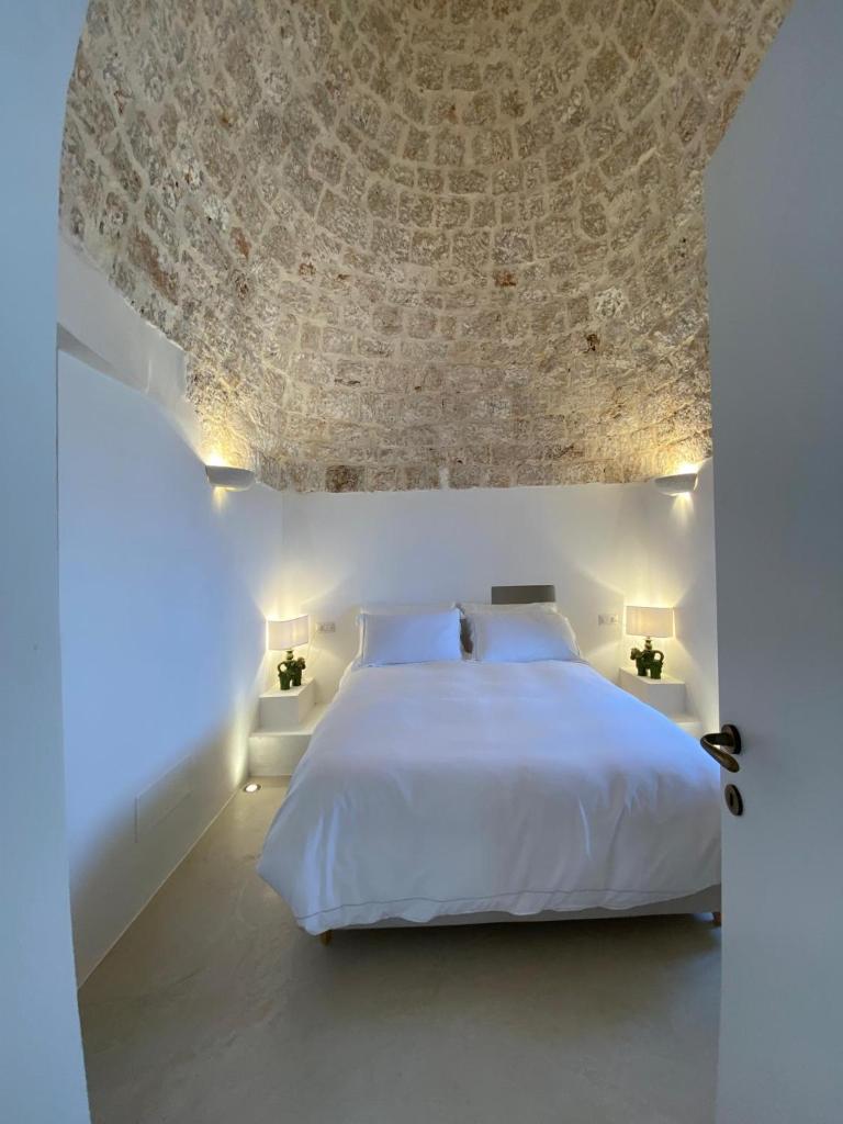 - une chambre avec un lit blanc et un plafond en pierre dans l'établissement Trulli della Chiesetta, à Selva di Fasano 15 autres photos