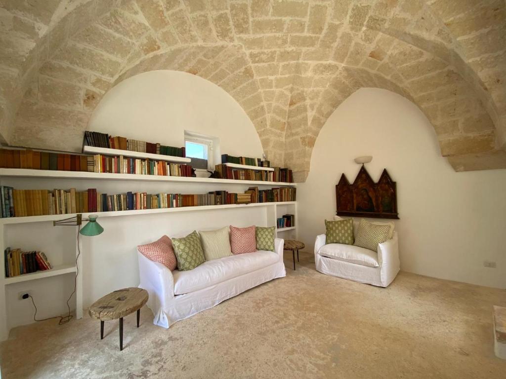 - un salon avec deux canapés et une bibliothèque dans l'établissement Trulli della Chiesetta, à Selva di Fasano