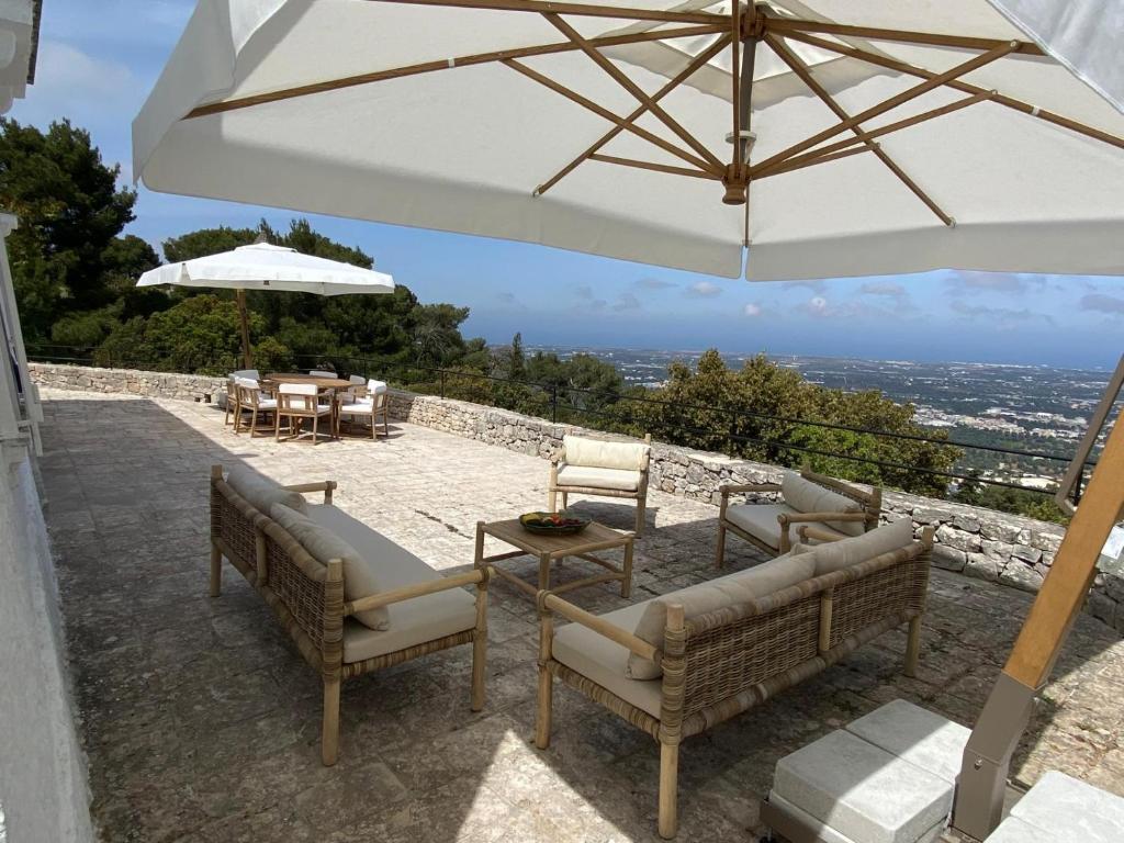 un patio avec deux chaises et un parasol dans l'établissement Trulli della Chiesetta, à Selva di Fasano