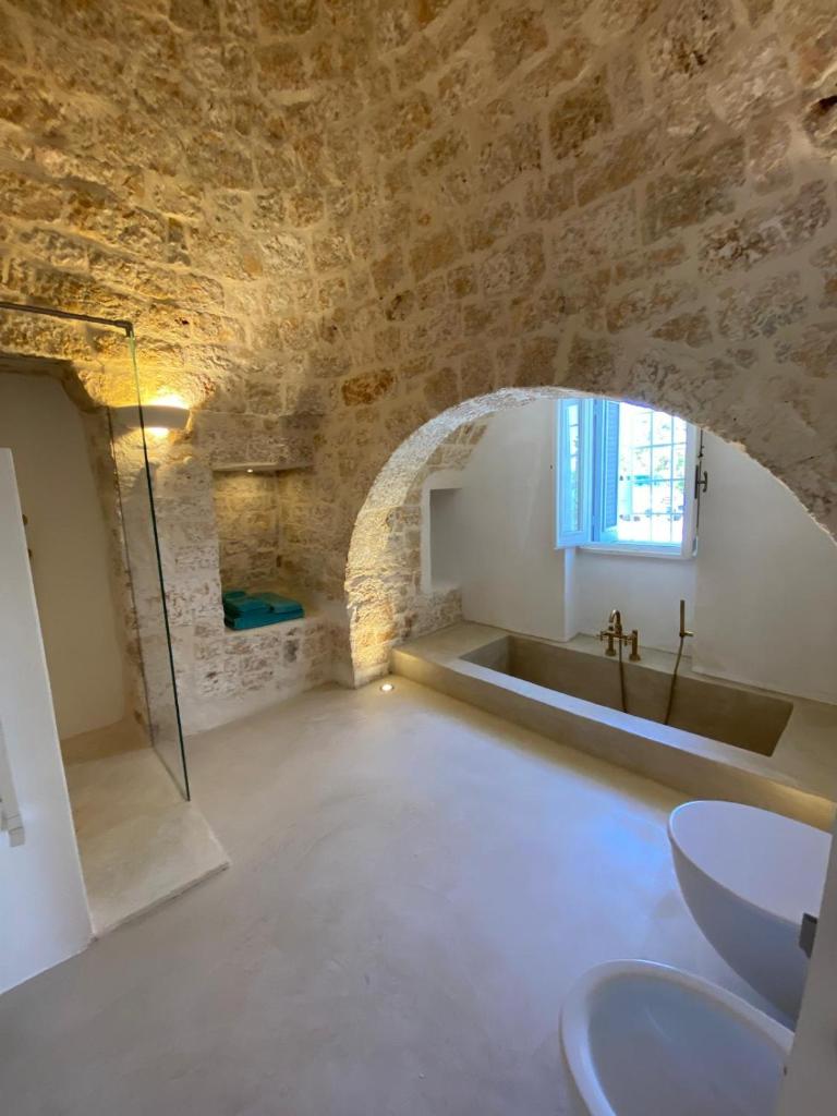 une grande pièce avec un lavabo et une baignoire dans l'établissement Trulli della Chiesetta, à Selva di Fasano