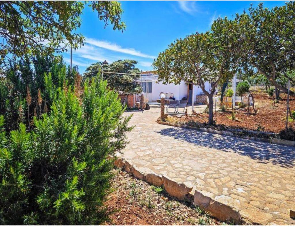 une passerelle en pierre devant une maison arborée dans l'établissement Villetta Nonna Maria, à San Vito Lo Capo
