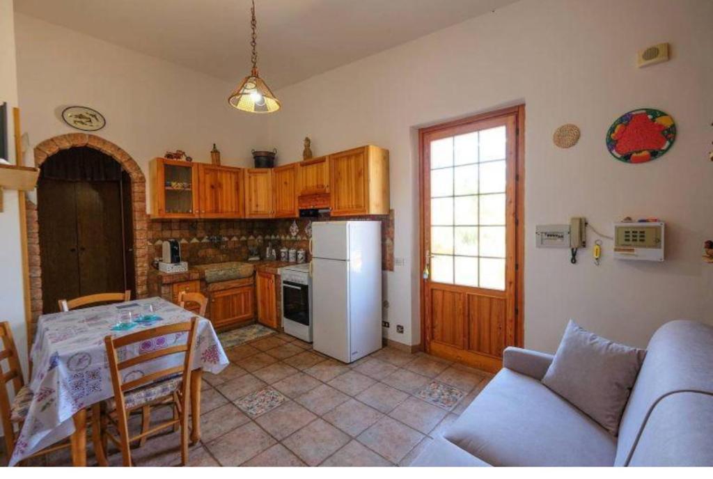 une cuisine avec une table et un réfrigérateur blanc dans l'établissement Villetta Nonna Maria, à San Vito Lo Capo