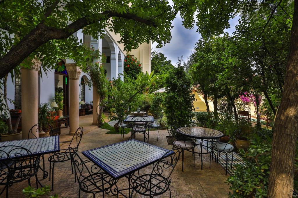 un patio extérieur avec des tables, des chaises et des arbres dans l'établissement Ryad Mabrouka, à Fès