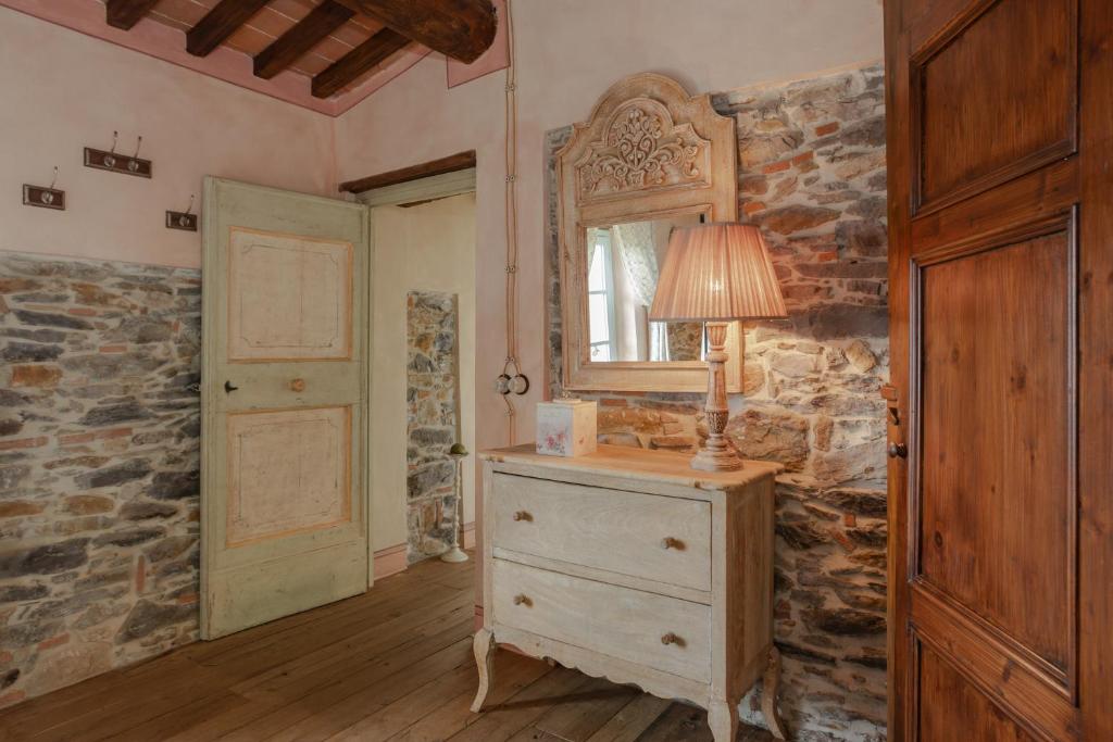 Cette chambre comprend une commode avec une lampe et un miroir. dans l'établissement Villa sii felice, à Buti