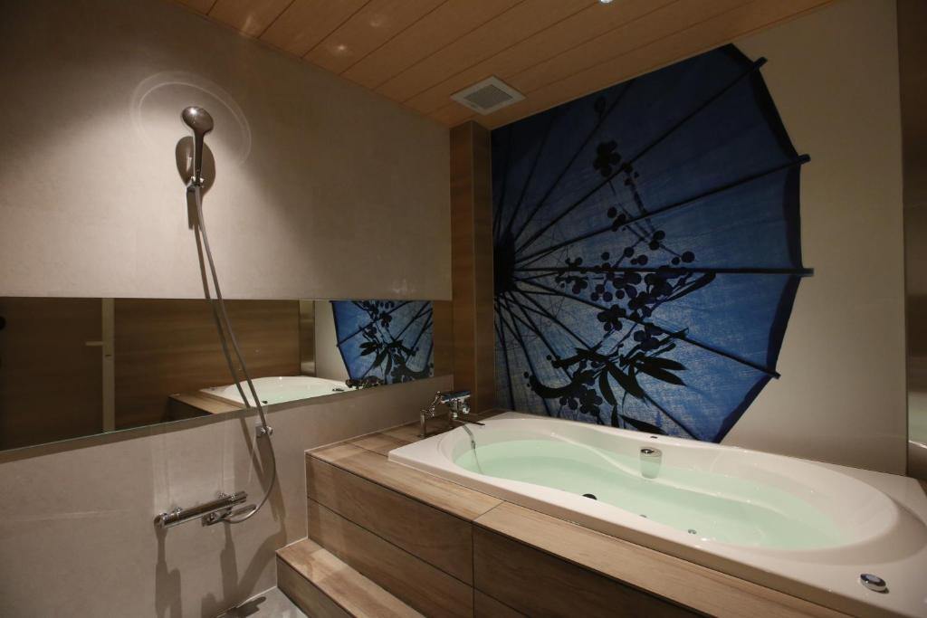 une salle de bain avec une baignoire et un grand miroir dans l'établissement HOTEL Miz, à Rifu