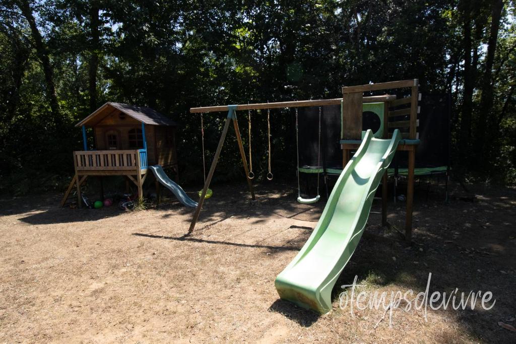 une aire de jeux avec un toboggan vert et une balançoire dans l'établissement Cottage O' Temps de Vivre, à Groléjac