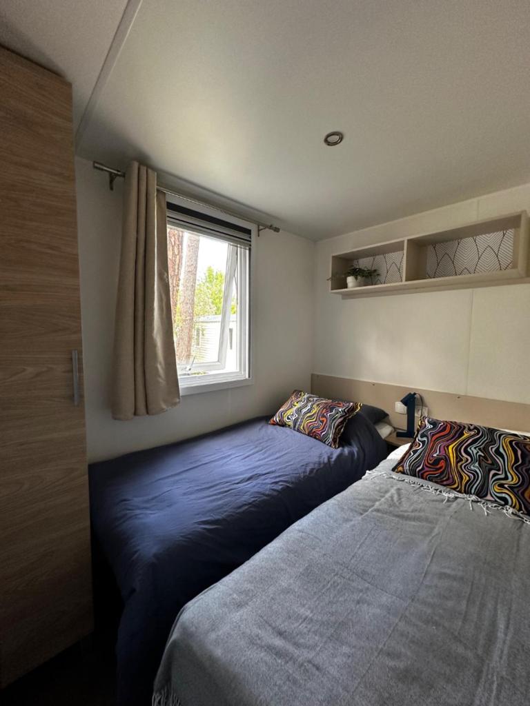 - une chambre avec deux lits à côté d'une fenêtre dans l'établissement Grand Mobil Home Tout Confort pour 6 personnes - Camping Les Oyats 4 étoiles, à Seignosse