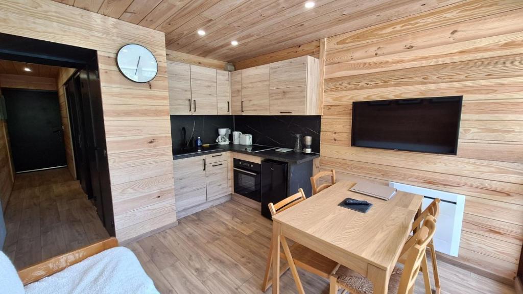 une cuisine et une salle à manger avec une table et une télévision dans l'établissement Appartement chaleureux en cœur de station, à Laruns