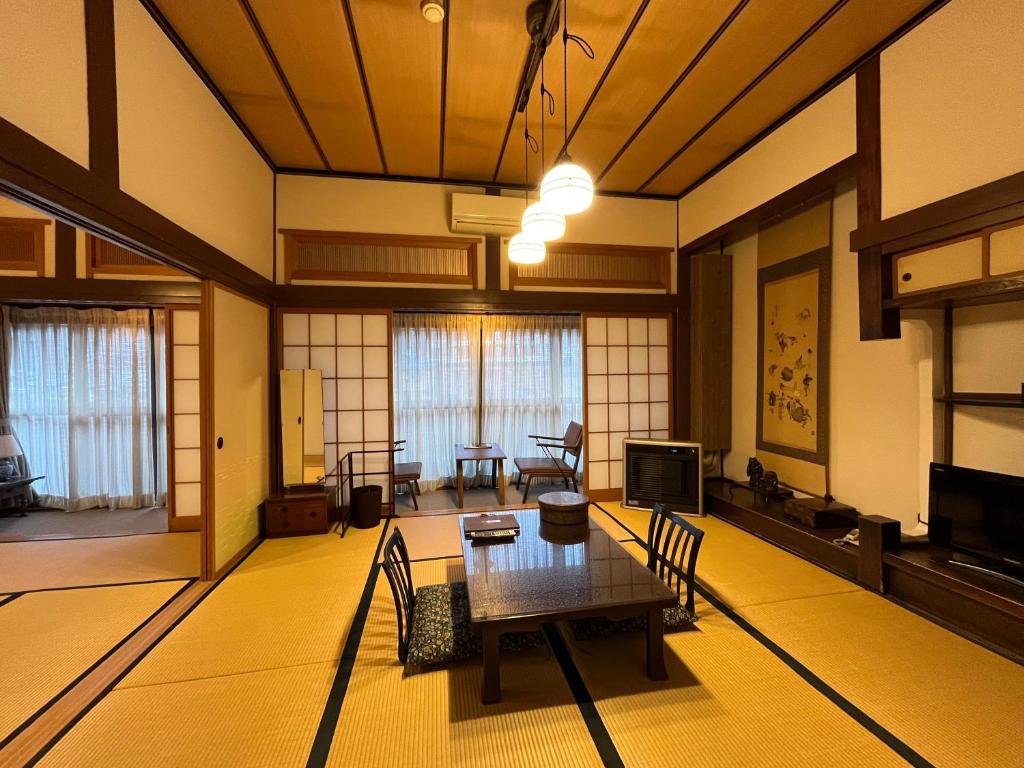 un salon avec une table et des chaises dans l'établissement Historical Ryokan SENYUKAN, à Ōwani