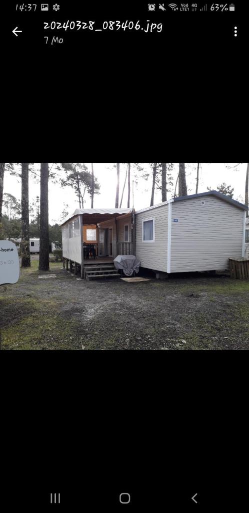 une petite caravane blanche avec une maison dans un champ dans l'établissement Vacances contis plage, à Saint-Julien-en-Born