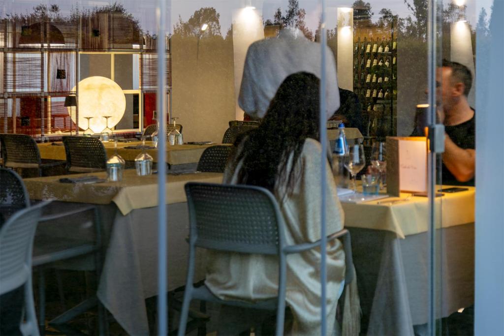 une femme assise sur une chaise dans un restaurant dans l'établissement Hotel San Teodoro, à San Teodoro