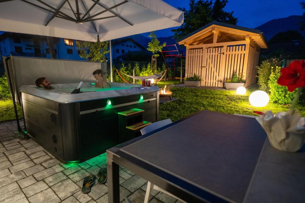 un homme dans une baignoire dans une arrière-cour la nuit dans l'établissement Caldonazzo Dog Sport & Wellness, à Caldonazzo