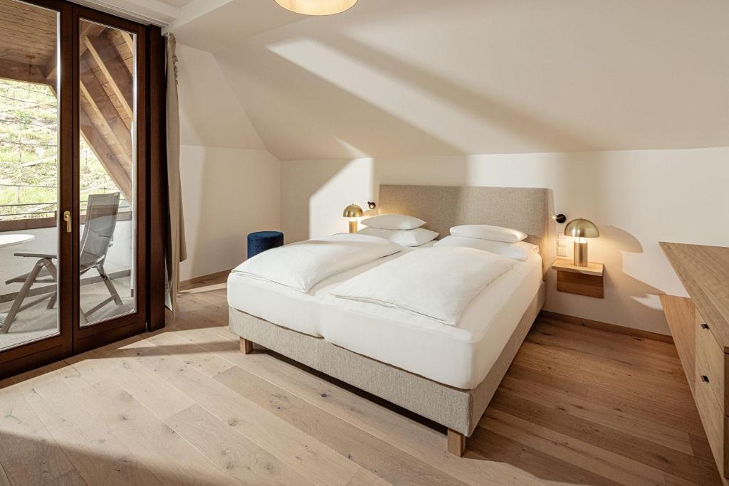 une chambre avec un lit blanc et une grande fenêtre dans l'établissement Hotel Haus am Hang, à Caldaro