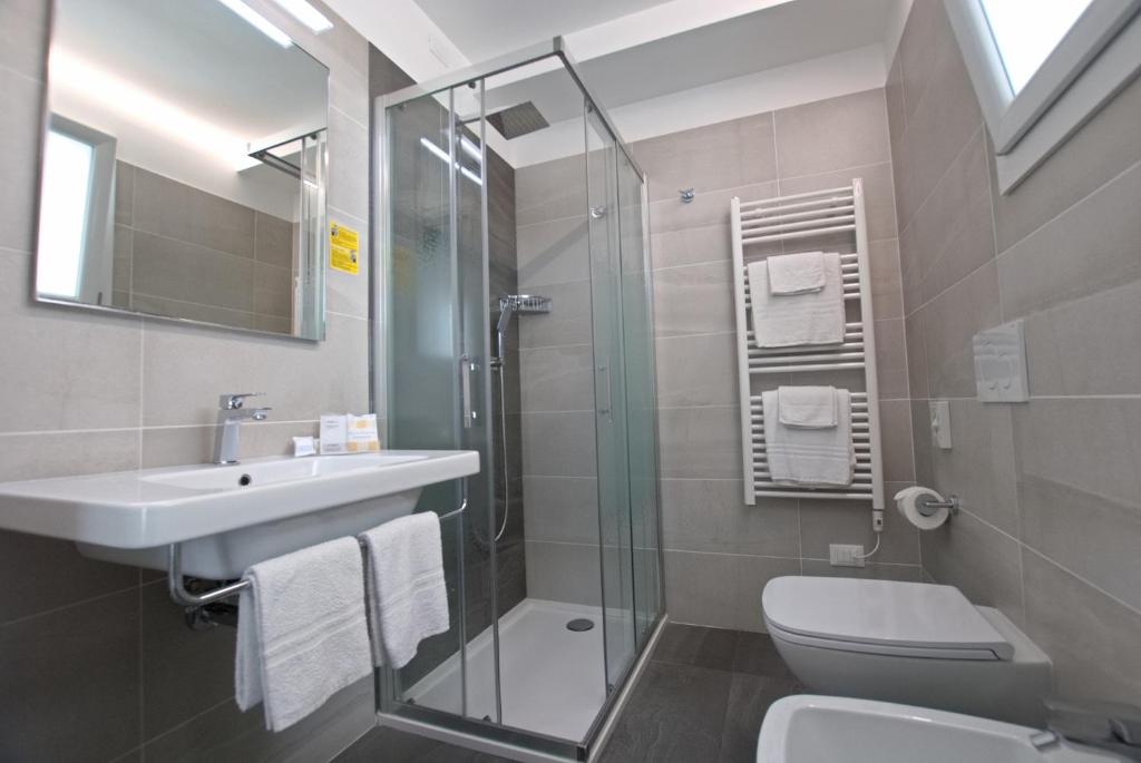 une salle de bain avec un lavabo, des toilettes et une douche dans l'établissement Hotel Paris, à Lignano Sabbiadoro