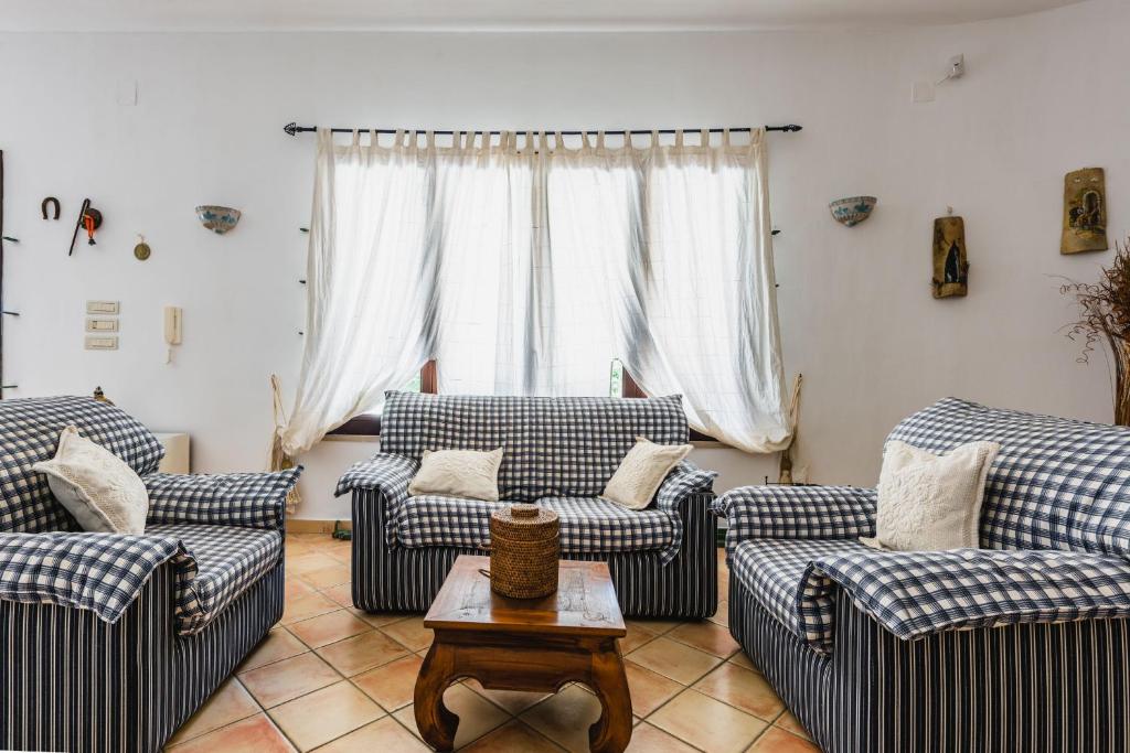 un salon avec des canapés bleus et blancs et une table dans l'établissement Villa Arenella con piscina, à Syracuse