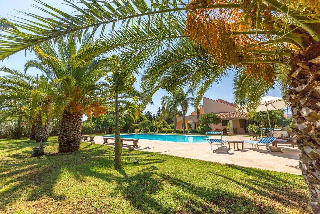 un complexe avec une piscine et un palmier dans l'établissement Villa Arenella con piscina, à Syracuse 31 autres photos