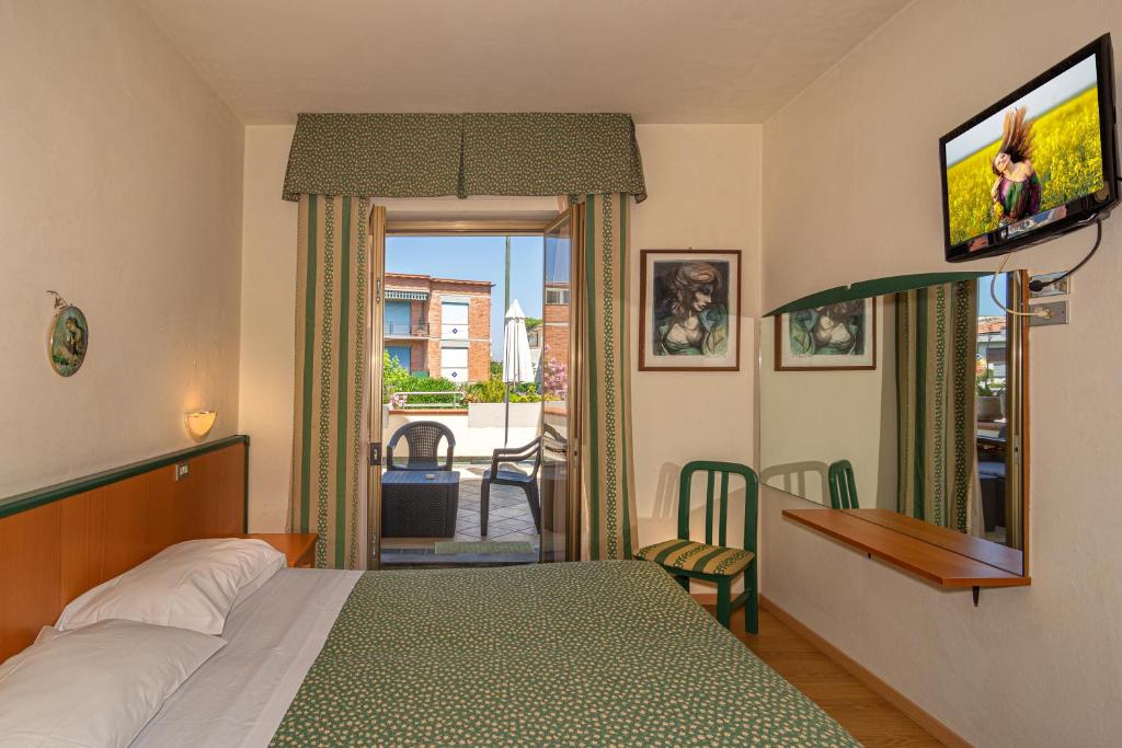 une chambre avec un lit et une télévision sur un mur dans l'établissement Hotel Mariani, à Lido di Camaiore