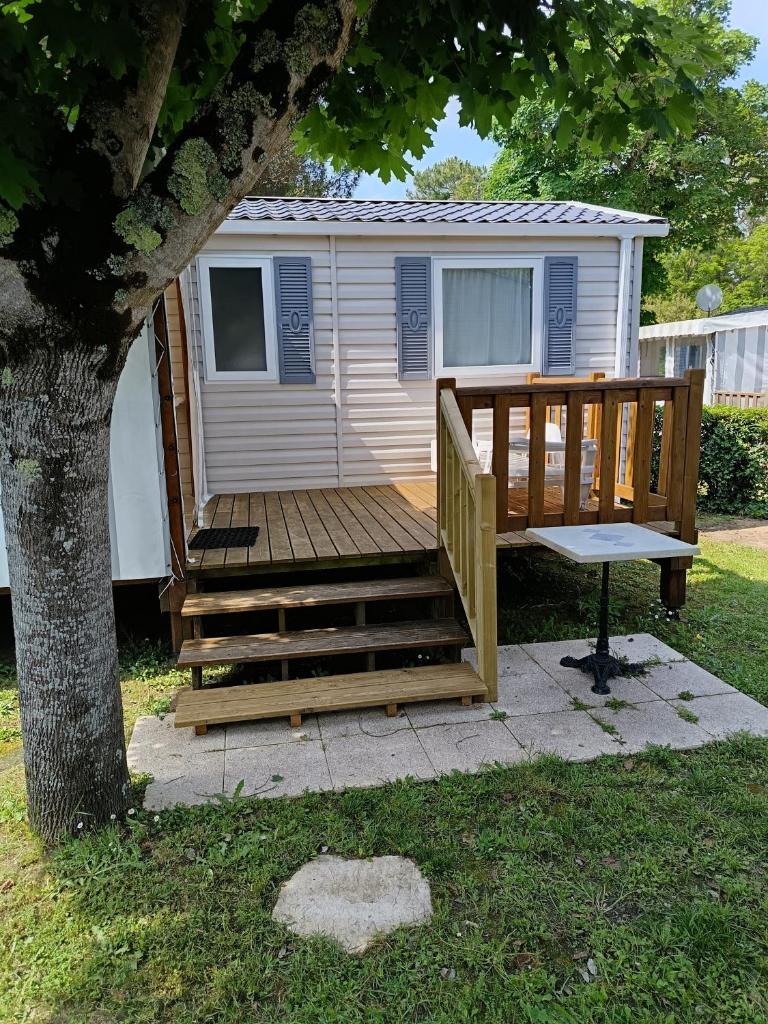 une cabane avec une terrasse à côté d'un arbre dans l'établissement MH 329 Camping Bois Dormant, à Saint-Jean-de-Monts