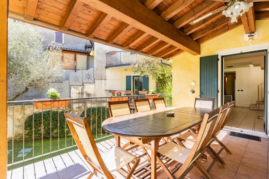 d'une terrasse avec une table et des chaises en bois sur un balcon. dans l'établissement "Il Vicolo" Sunny Lake Garda Villa, à Toscolano Maderno
