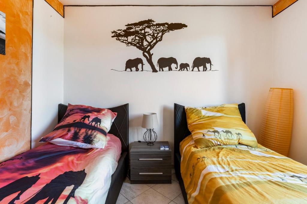 - une chambre avec 2 lits et un arbre sur le mur dans l'établissement "Il Vicolo" Sunny Lake Garda Villa, à Toscolano Maderno