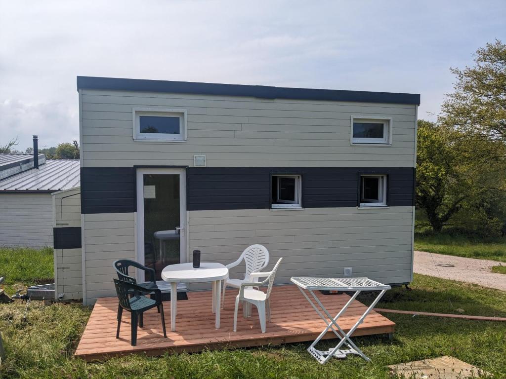 une petite maison avec une table et des chaises sur une terrasse dans l'établissement Tiny House proche de la plage sans draps ni serviettes, à Plévenon