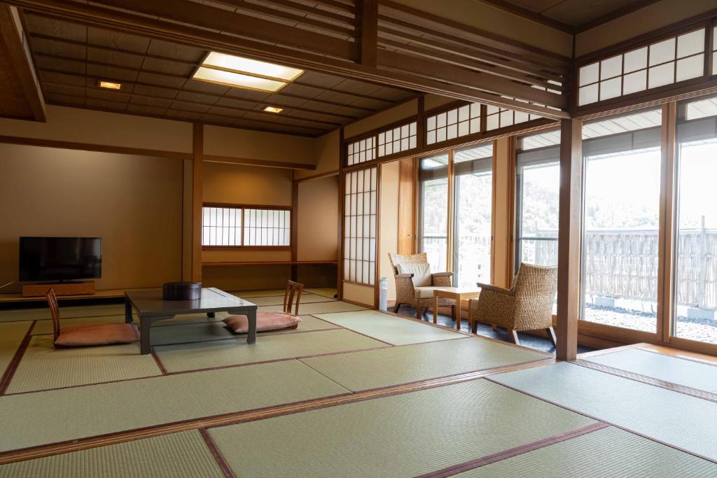 un salon avec une table, des chaises et des fenêtres dans l'établissement Izumiso, à Matsumoto