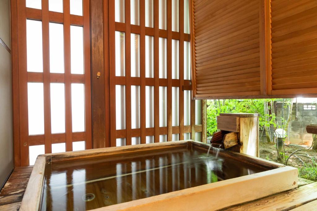 - une grande piscine d'eau dans une chambre avec fenêtres dans l'établissement Izumiso, à Matsumoto