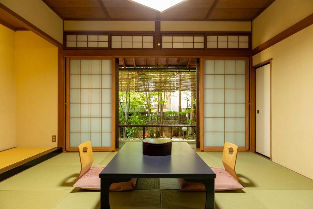 une pièce avec une table et deux chaises et une fenêtre dans l'établissement Izumiso, à Matsumoto