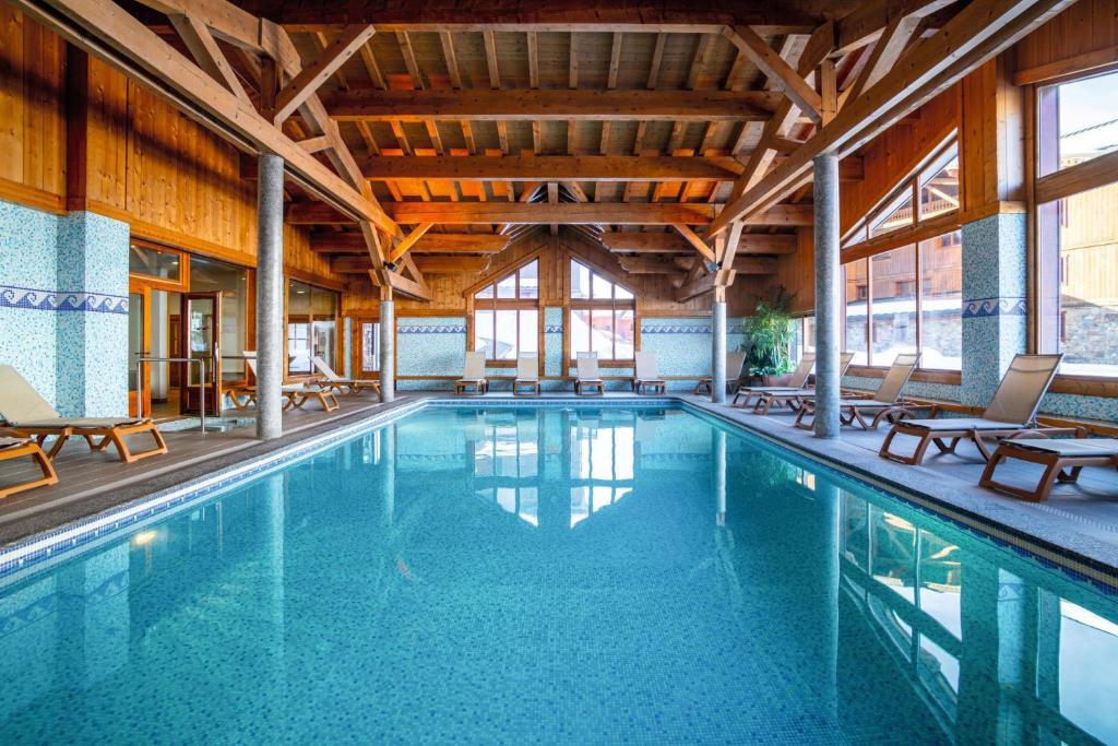 une grande piscine avec des chaises dans un bâtiment dans l'établissement Belambra Clubs Résidence Les Menuires - Le Hameau Des Airelles, aux Menuires