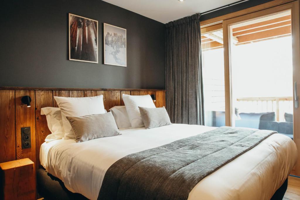 une chambre avec un grand lit avec des oreillers blancs dans l'établissement Duplex Encombres by Lodji, à Saint-Martin-de-Belleville