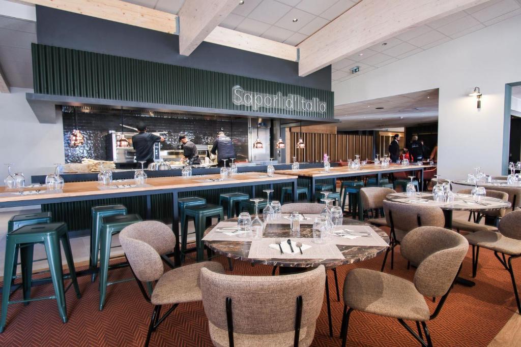 un restaurant avec des tables et des chaises et un bar dans l'établissement Belambra Clubs Les 2 Alpes Les Crêtes, à Les Deux Alpes