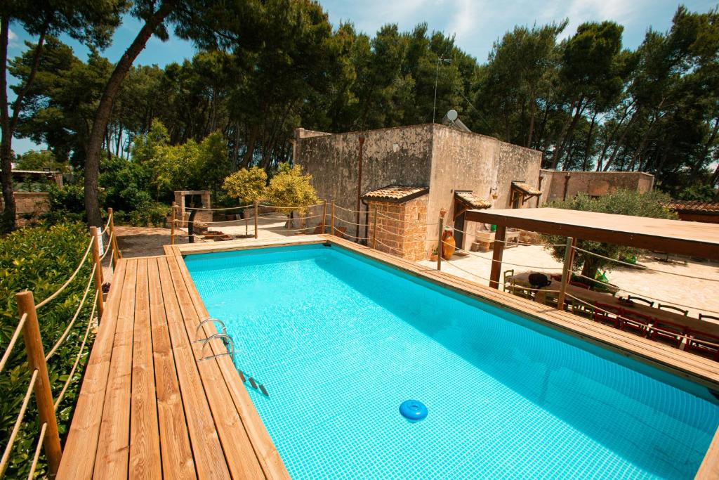 une piscine avec une terrasse en bois à côté d'une maison dans l'établissement villa dei cento Pini, à Monteroni di Lecce