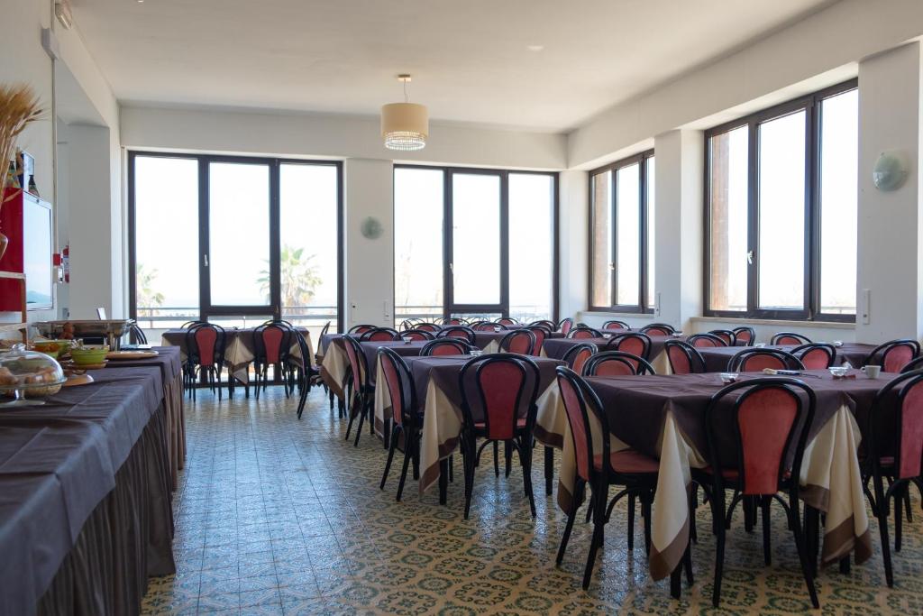une grande pièce avec des tables, des chaises et des fenêtres dans l'établissement Hotel Re Leone, à Rimini
