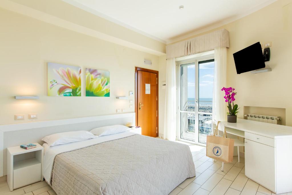 une chambre avec un lit, un bureau et une fenêtre dans l'établissement Hotel Lungomare, à Cervia