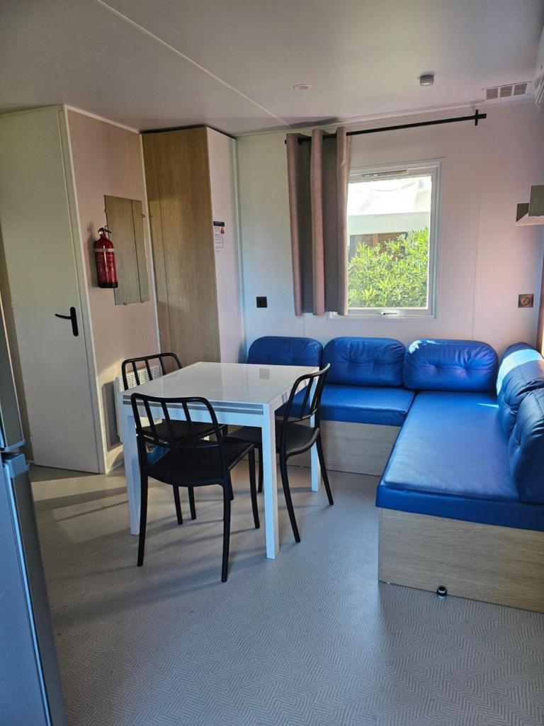 un salon avec une table et un canapé bleu dans l'établissement Mobilhome 6 personnes camping la falaise, à Narbonne
