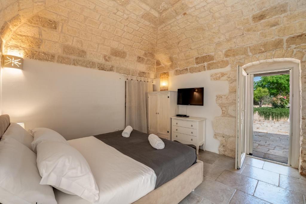 une chambre avec un lit, une télévision et une fenêtre dans l'établissement Villa Gli Arcangeli, à Ostuni