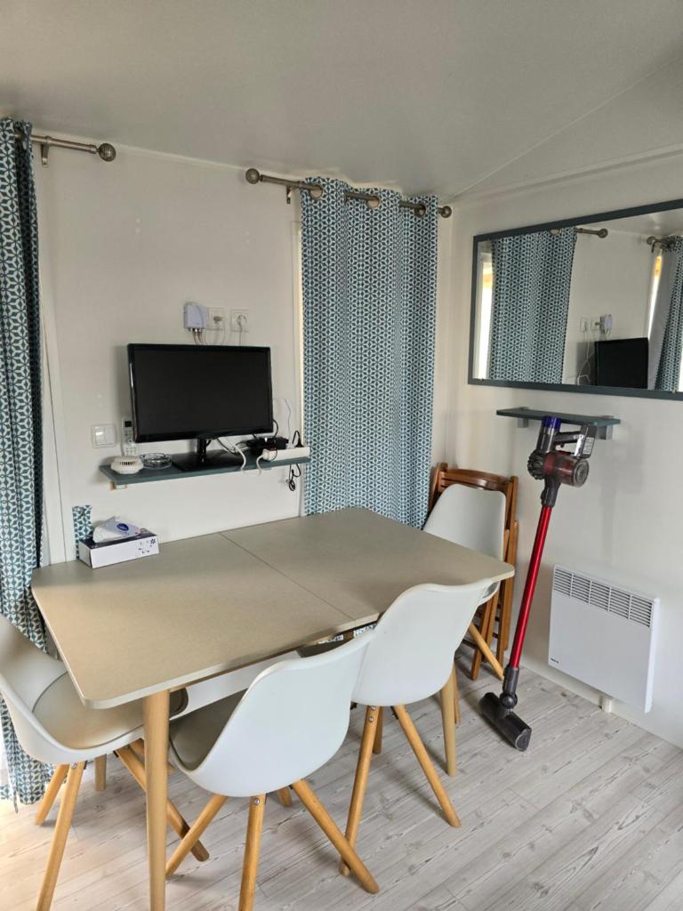 une salle à manger avec une table, des chaises et une télévision dans l'établissement Mobil home camping les Viviers 8 personnes, à Lège-Cap-Ferret
