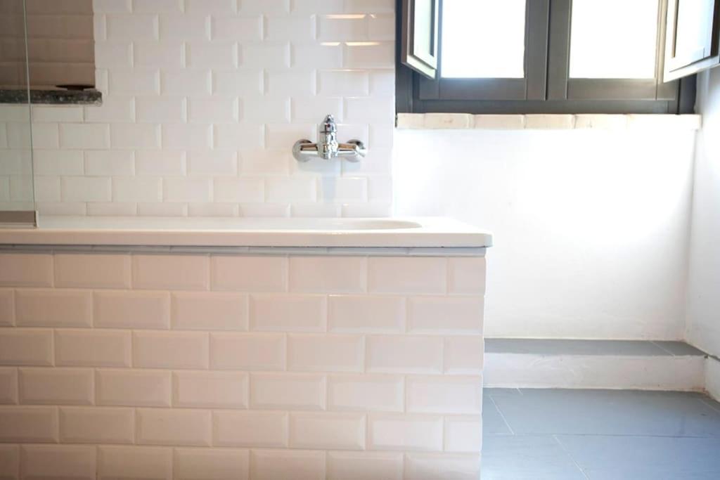 La salle de bains est pourvue de carrelage blanc, d'un lavabo et d'une fenêtre. dans l'établissement Family friendly chic Italian farmhouse with pool, à Mogliano 16 autres photos