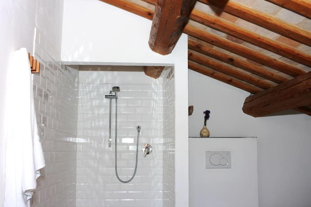 une douche dans une salle de bain aux murs blancs et aux plafonds en bois dans l'établissement Family friendly chic Italian farmhouse with pool, à Mogliano