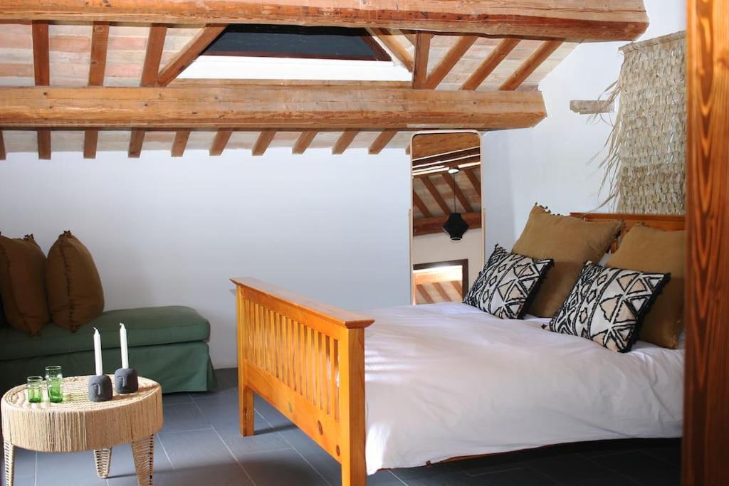 une chambre avec un lit en bois et un canapé vert dans l'établissement Family friendly chic Italian farmhouse with pool, à Mogliano